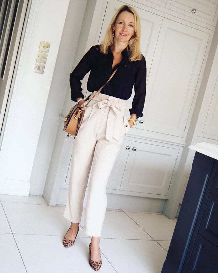 Karen wearing a black blouse and tie waist white pants | 40plusstyle.com