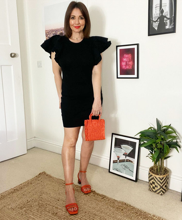 Nikki wears orange accessories with her black dress | 40plusstyle.com