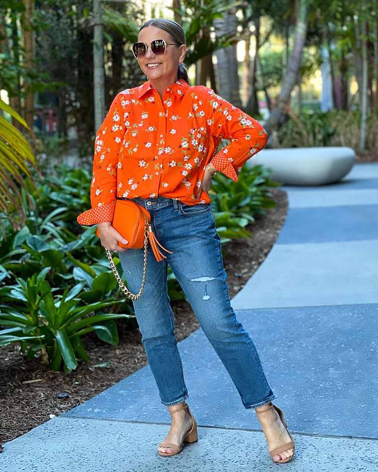 Jona wears an orange print blouse with her jeans | 40plusstyle.com