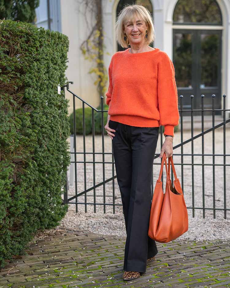 Greetje in an orange outfit and jeans | 40plusstyle.com